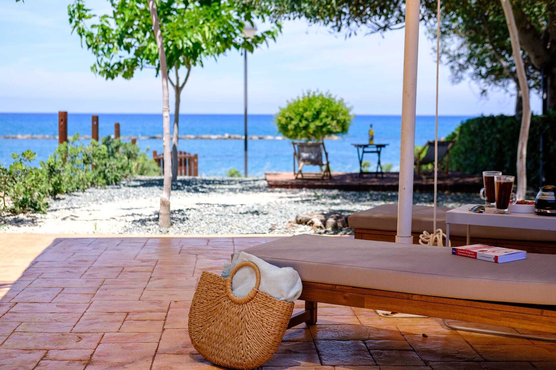 A beachside lounge with a wicker basket, a cushioned seating area, and a view of the sea.