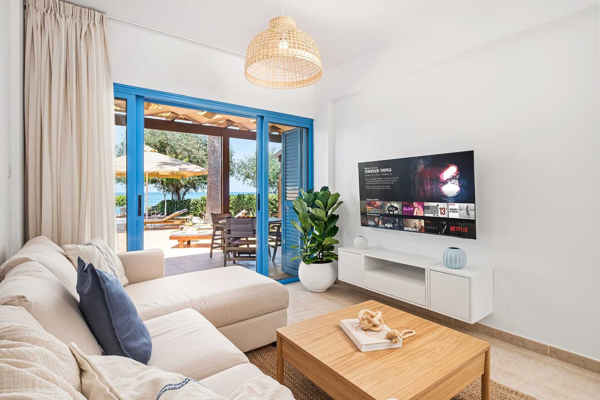 Uma sala de estar moderna com sofá, mesa de centro, televisão e vista para o exterior.