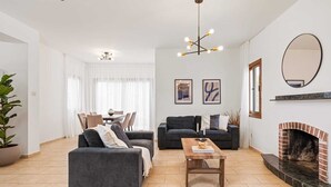 Una sala de estar moderna con chimenea, dos sofás, un comedor y un espejo grande.