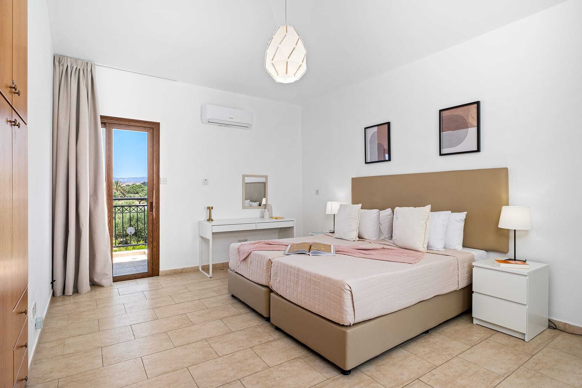 Ein Schlafzimmer mit Bett, Nachttischen, Schreibtisch, Stuhl, Spiegel und Blick ins Freie.
