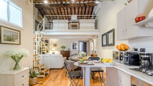 Uma cozinha espaçosa com área de jantar, piso de madeira e um quarto no mezanino com varanda.