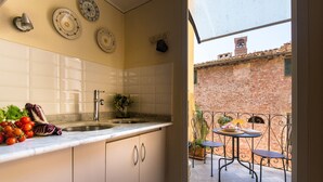 Uma cozinha com armários brancos, pia e bancada com produtos frescos.