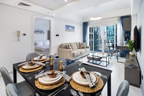 Ein modernes Wohnzimmer mit Essbereich, einer Couch, einem Fernseher und einem Balkon mit Blick auf die Stadt.