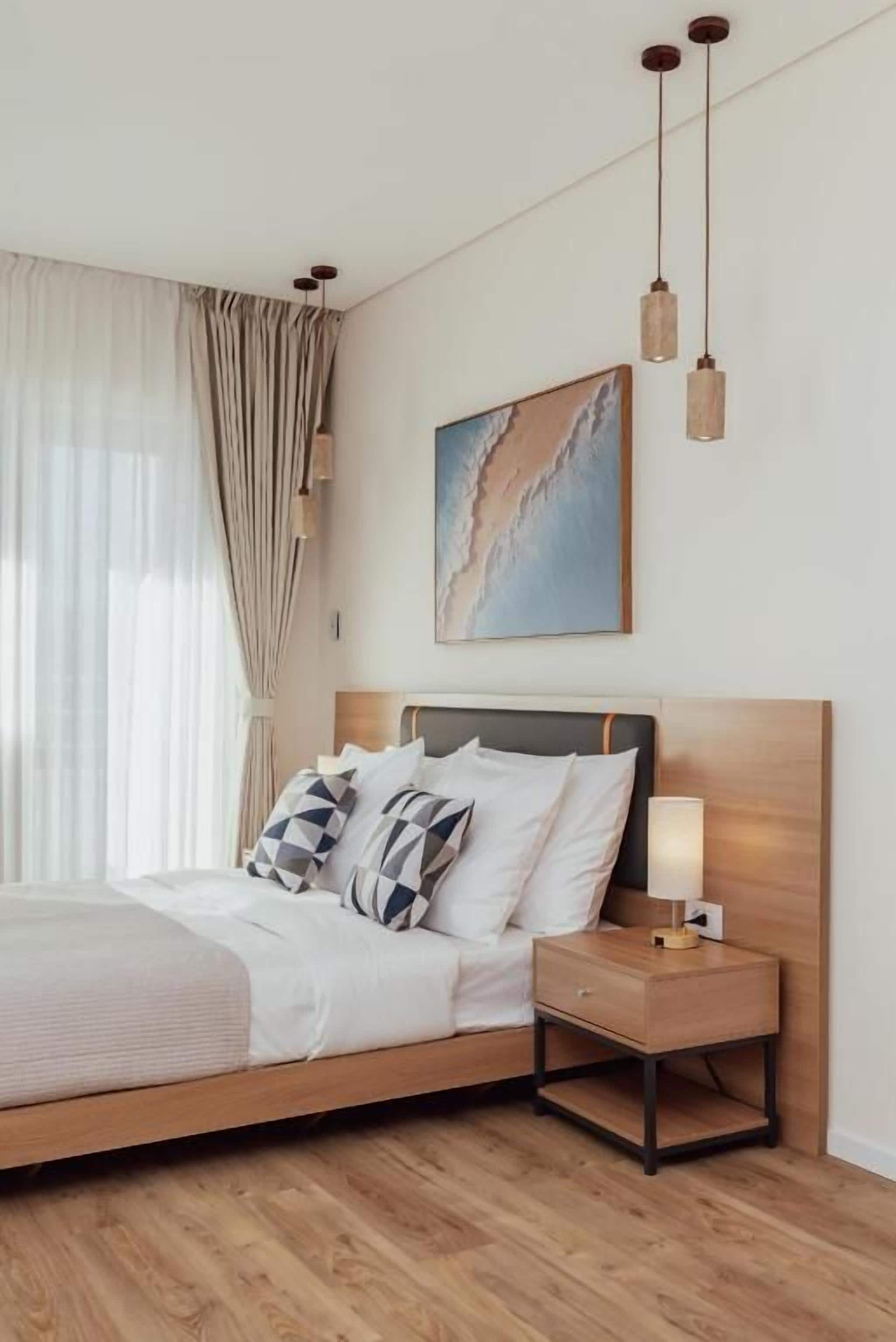 A neatly arranged bedroom with a bed, bedside table, and a painting on the wall.