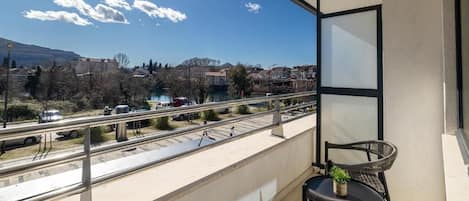 Ein Balkon mit Blick auf einen Fluss, eine Brücke und entfernte Gebäude.