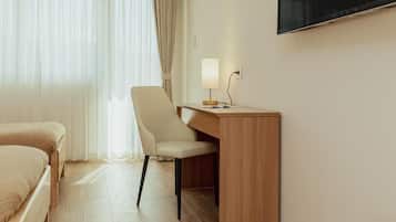 A hotel room with a bed, a desk, a chair, a TV, and a window with curtains.