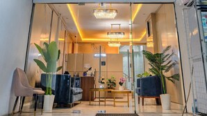 Der Eingangsbereich der Palm Grove Villas mit Rezeption, Sitzgelegenheiten und einer Chandelier.