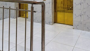 Eine Lobby mit Marmorwänden, zwei Aufzügen und einem Metallgeländer.