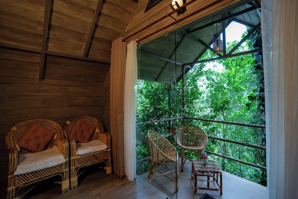 Un interior de madera con mobiliario de mimbre y vistas a vegetación exuberante.