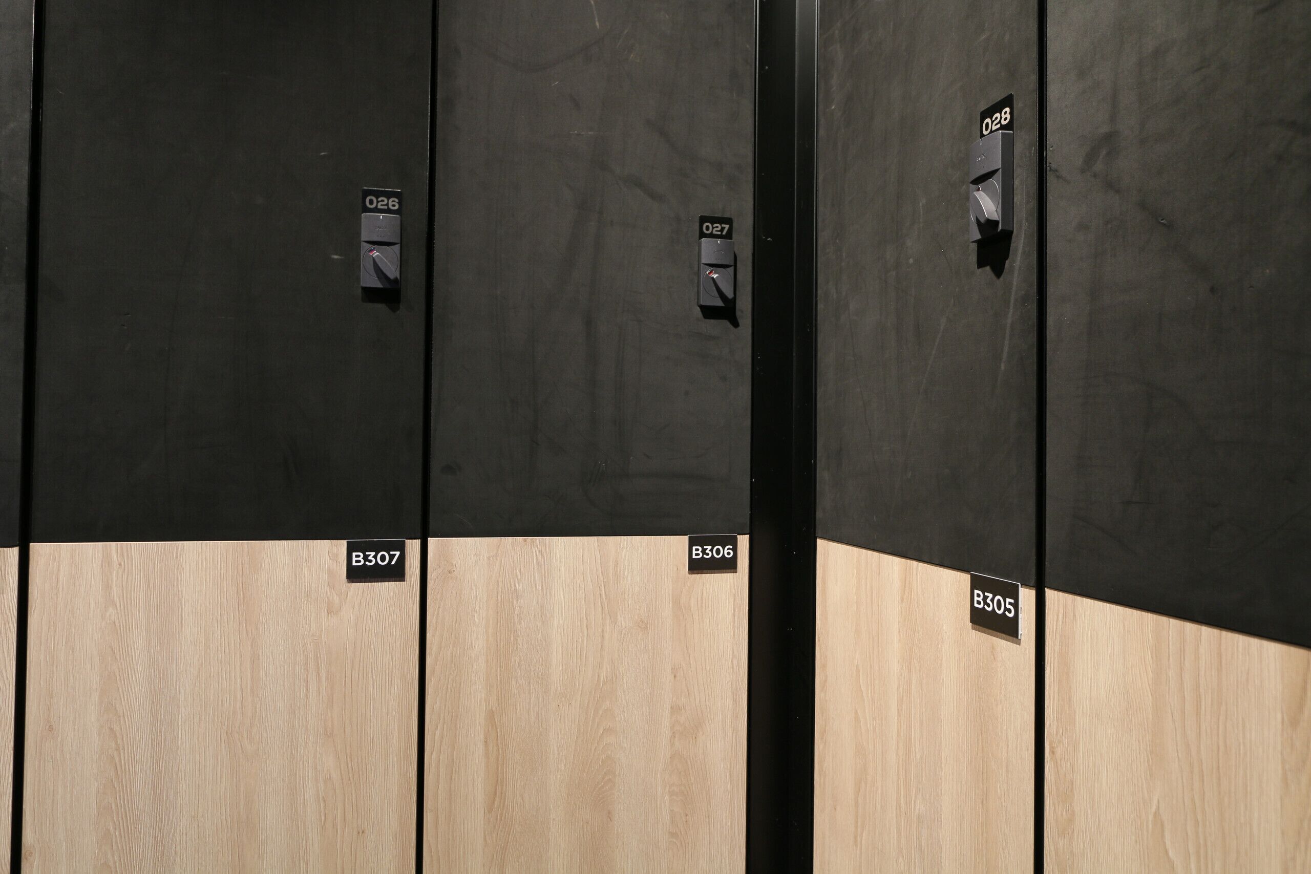 Una fila de puertas de madera oscura y clara con los números de habitación B307, B306 y B305.