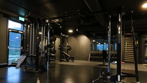 Un gimnasio con equipamiento de levantamiento de pesas, una barra de dominadas y una máquina elíptica.