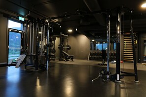 Un gimnasio con equipamiento de levantamiento de pesas, una barra de dominadas y una máquina elíptica.