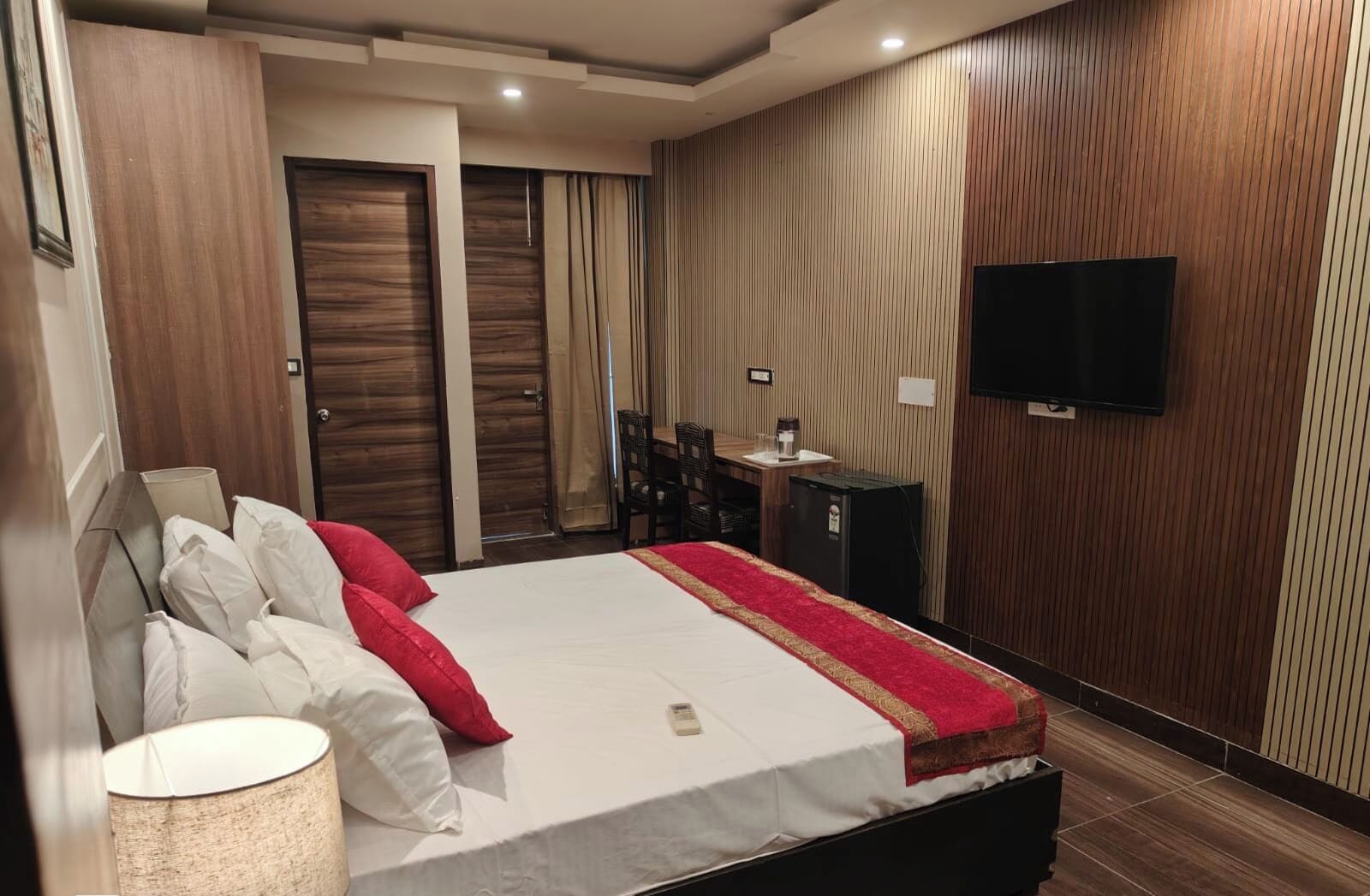 A hotel room with a bed, a desk, a television, and a minibar.