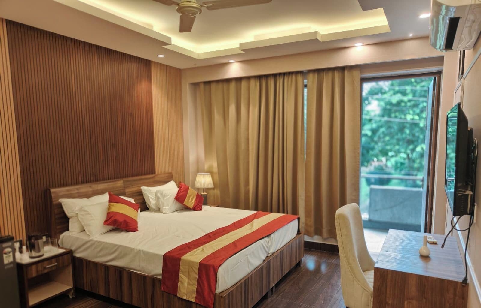 A hotel room with a bed, bedside table, lamp, and a view of greenery outside.