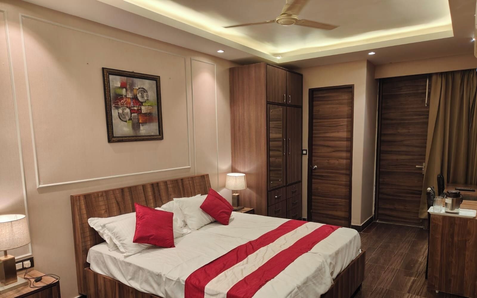 A hotel room with a bed, a nightstand, a lamp, a wardrobe, and a ceiling fan.