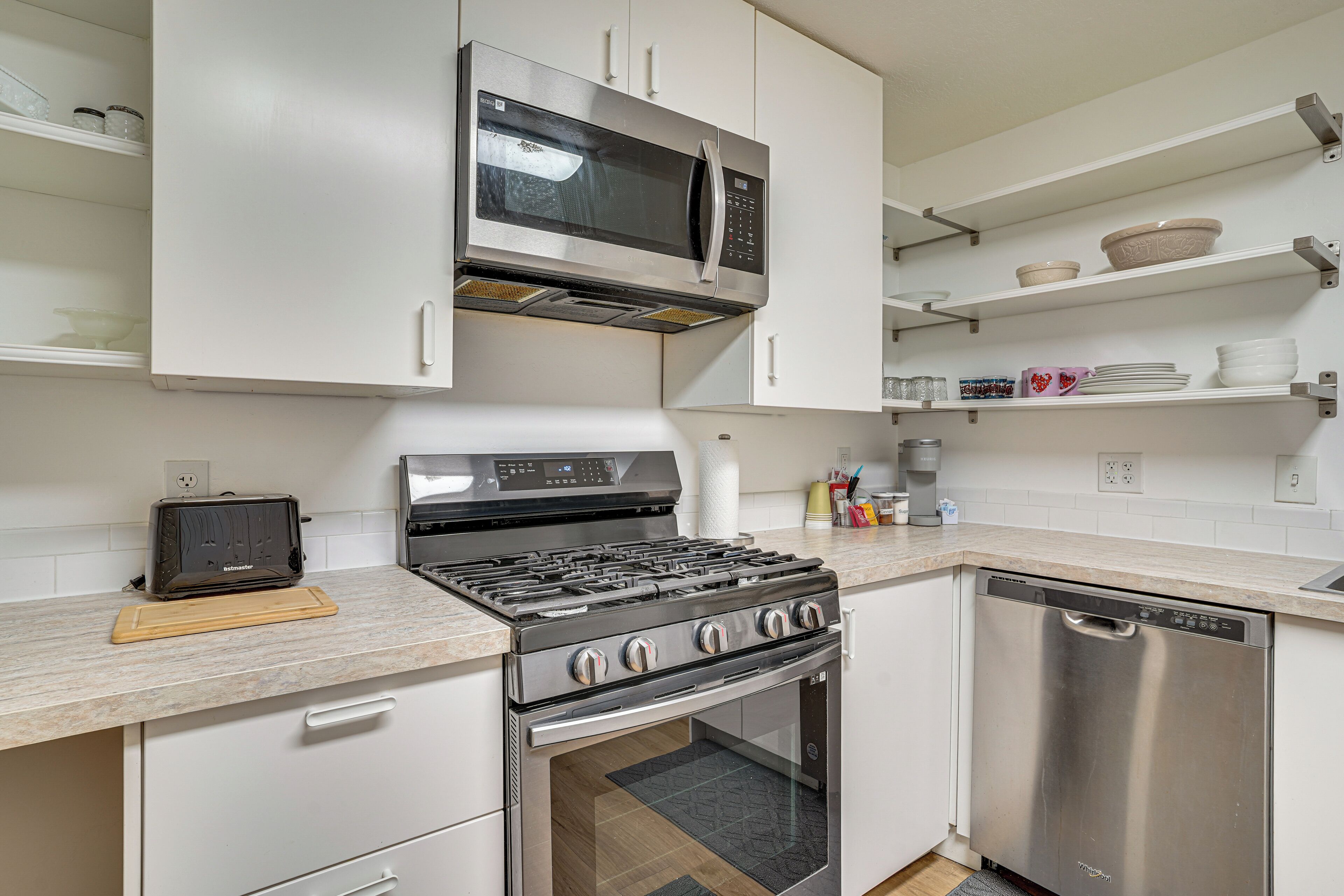 Una cocina moderna con microondas de acero inoxidable, cocina a gas y lavavajillas.