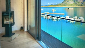 Ein Zimmer mit großem Fenster mit Blick auf eine Marina, in der Boote liegen, und einen Berg.