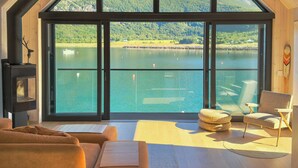 Ein modernes Interieur mit einem großen Panoramafenster, einem Kamin und einer gemütlichen Sitzecke.