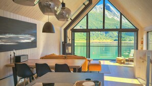 Ein modernes Interieur mit Essbereich, Holzwänden und einem großen Fenster mit Seeblick.