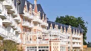 Een meerlaags hotel met balkons, een geruit patroon op de gevel en een heldere lucht.