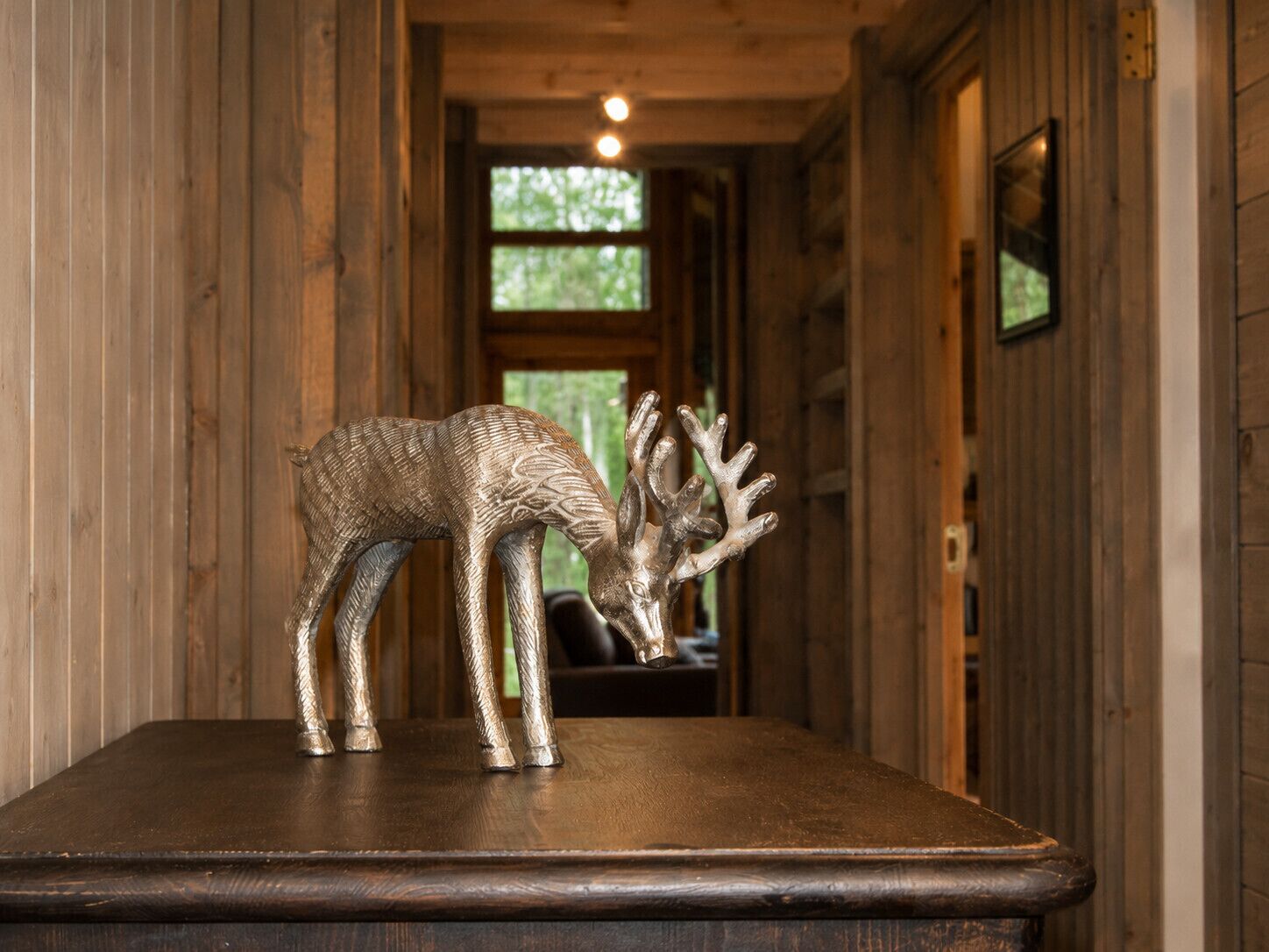 Un intérieur en bois où l’on aperçoit une table sur laquelle est exposée une sculpture de cerf en métal.