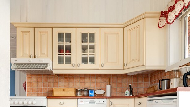 A kitchen with white cabinets, a stove, a dishwasher, and a tiled floor. - Private cabin by the sea, Lofoten (Vestvågøy)
