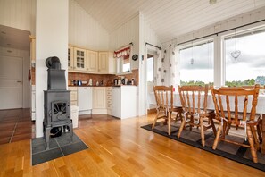 A kitchen with wooden cabinets, a stove, and a dining area with wooden chairs.