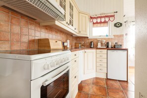 A kitchen with a stove, oven, white cabinets, and a refrigerator.
