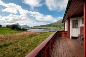 A wooden deck with a view of a lake and mountains.
