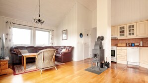 A spacious living room with a sofa, a chair, a wooden table, and a fireplace. - Private cabin by the sea, Lofoten (Vestvågøy)