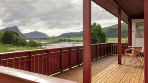 A wooden deck with a view of a river and mountains. - Private cabin by the sea, Lofoten (Vestvågøy)