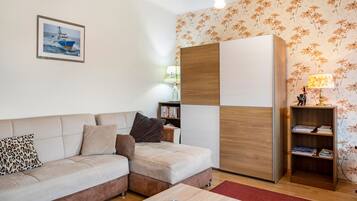 Ein Wohnzimmer mit einer Couch, einem Couchtisch, einem Bücherregal und einer Wand mit Blumenmuster-Tapete.