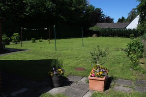 Ein gepflegter Rasen mit einem Pflasterweg, ein kleiner Garten mit Blumen und ein Haus im Hintergrund.