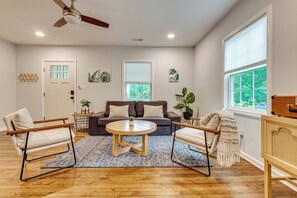 Ein geräumiges Wohnzimmer mit einer Couch, zwei Sesseln, einem Couchtisch und einem Deckenventilator.