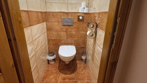 Ein kleines Badezimmer mit Toilette, zwei Mülleimern und einem Händetrockner.