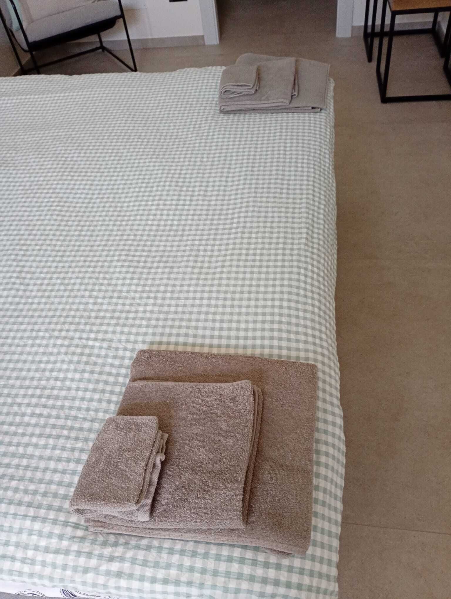 Un lit avec une couverture à carreaux, une serviette pliée et une couverture pliée posées dessus.