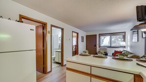 Une cuisine équipée d’un réfrigérateur, de meubles de rangement en bois, d’un plan de travail avec de la vaisselle et d’une fenêtre.