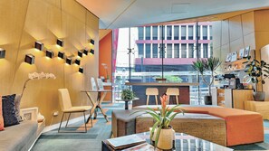 Eine moderne Lobby mit Glastisch, Sitzgruppe und Blick auf die Stadtlandschaft.