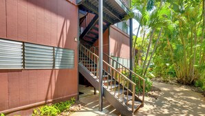 Un bâtiment doté d’un escalier menant à un étage supérieur, entouré de verdure.