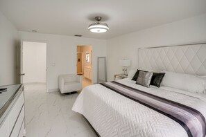 Ein Schlafzimmer mit Bett, Stuhl, Nachttisch, Lampe und Deckenleuchte.