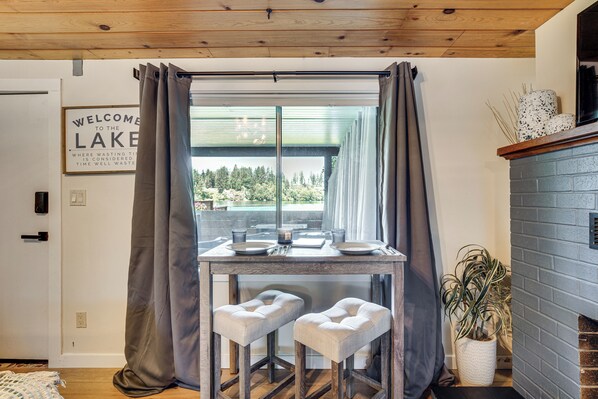 A dining area with a table, two cushioned stools, a potted plant, and a fireplace. - Tanwax Lake Waterfront Studio w/ Private Hot Tub! (Eatonville)