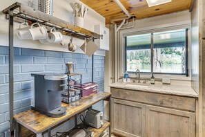 A kitchen with a coffee machine, utensils, and a window with a view. - Tanwax Lake Waterfront Studio w/ Private Hot Tub! (Eatonville)