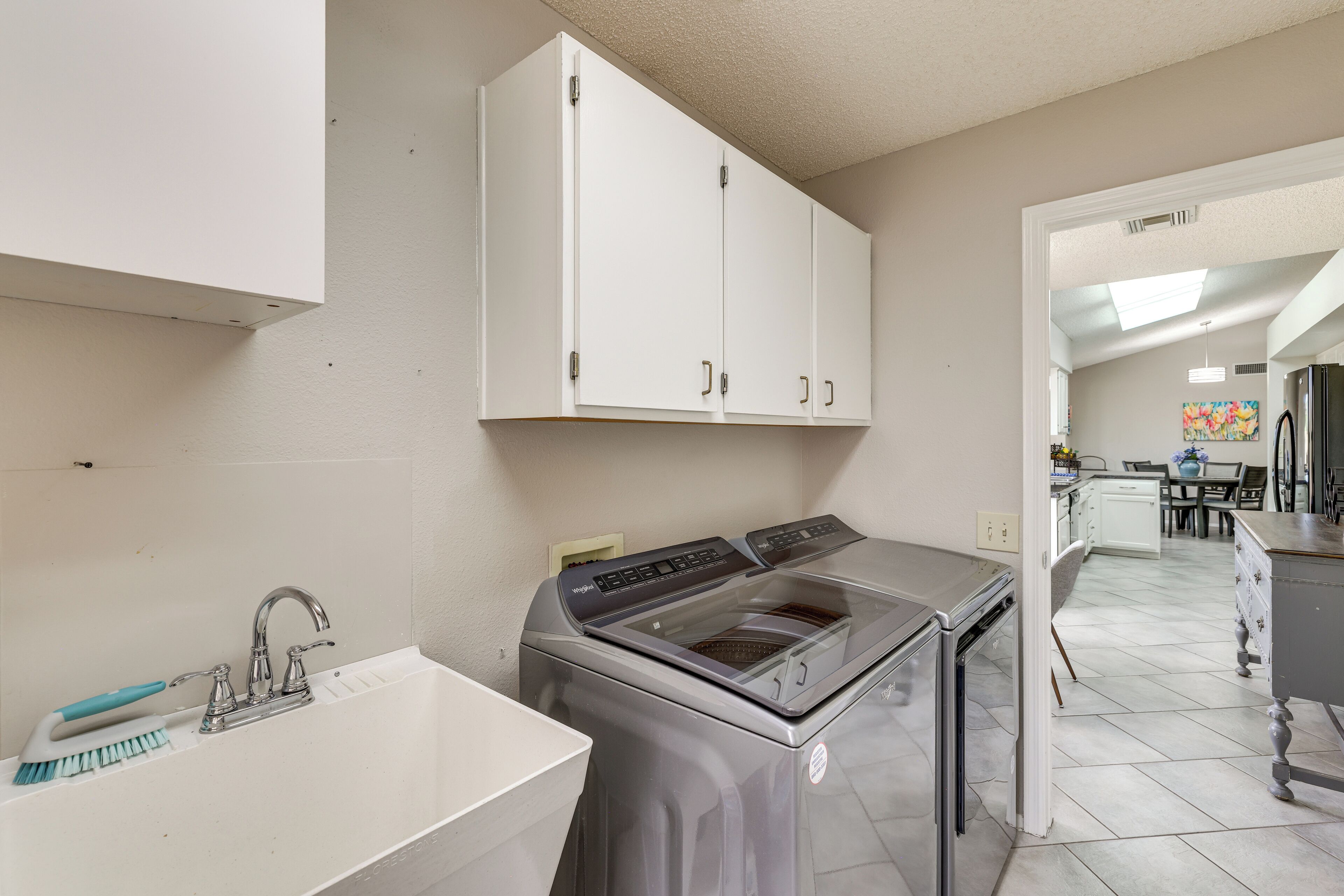 A kitchen with a washing machine, a sink, and cabinets.