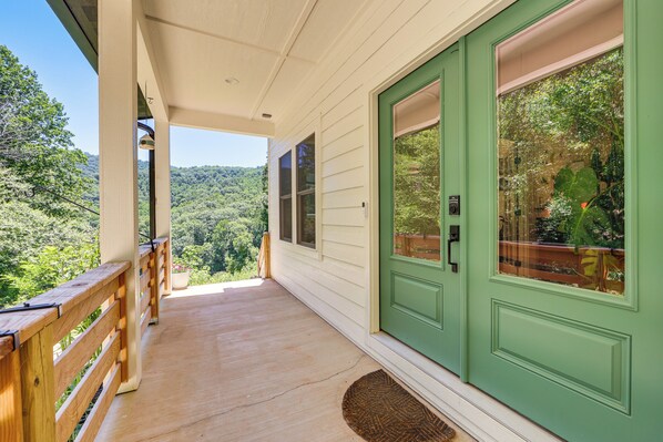 A porch with a wooden railing, a green door, and a view of a forested hillside. - Deck & Fire Pit! Mtn Escape, 12 Mi to Asheville (Leicester)