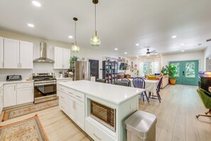 A modern kitchen with white cabinets, a central island, and a dining area with a table and chairs. - Deck & Fire Pit! Mtn Escape, 12 Mi to Asheville (Leicester)