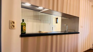 A kitchen with a black countertop, a stainless steel sink, a green bottle, and a mirror above the counter. - 4-Guest Elegant Holiday Base in Hotton (Hotton)