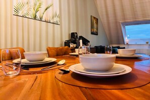 Une table à manger dressée avec des bols, des assiettes, des couverts et un verre.