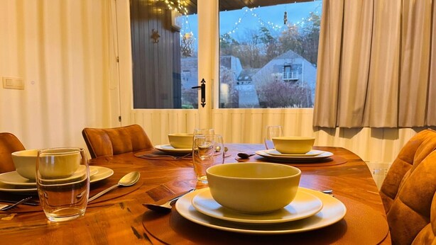 A dining table set with bowls, plates, and glasses, with a window view of a building and trees. - 4-Guest Elegant Holiday Base in Hotton (Hotton)