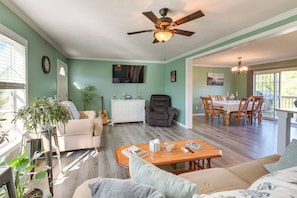 A living room with a sofa, coffee table, and a dining area with chairs and a table.