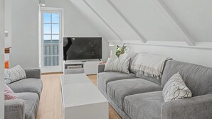 Et moderne loftværelse med stort vindue, fladskærms-tv og hyggeligt siddeområde.